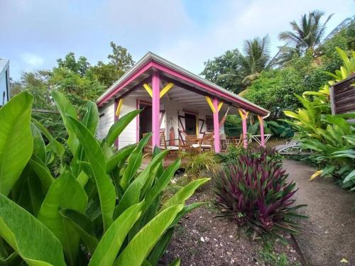 ein kleines Haus mit rosa Säulen im Garten in der Unterkunft Bungalow Bougainvilliers in Sainte-Anne