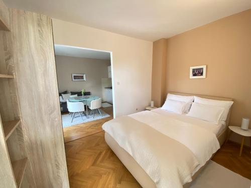 a bedroom with a white bed and a dining room at Apartments Flora 2 in Rab