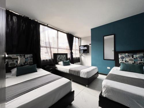 1 dormitorio con 2 camas y pared azul en Hotel HILLS BOGOTA en Bogotá