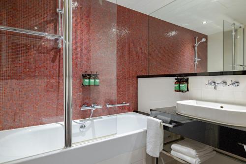 uma casa de banho com uma banheira, um lavatório e um chuveiro em Crowne Plaza Amsterdam - South, an IHG Hotel em Amesterdão
