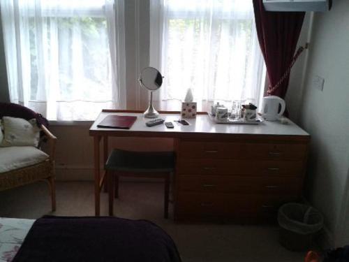 a bedroom with a desk with a lamp and a window at The Caraneal in Plymouth