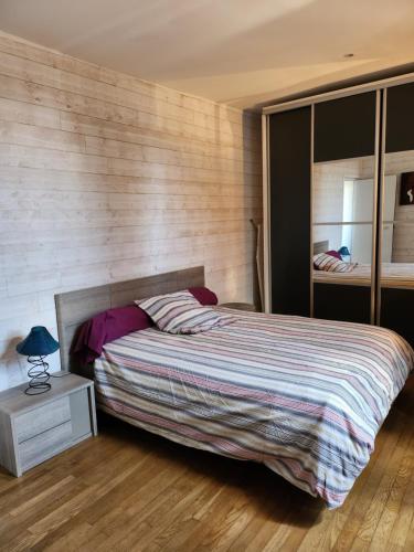 une chambre avec un lit et un mur en bois dans l'établissement la chambre de Jeremy, à La Bachellerie