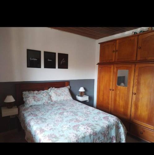 een slaapkamer met een bed en een houten kast bij casa temporada da Cris in Paraty