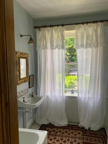 Ballyteige Bridge的住宿－Ballyteige Lodge，浴室设有白色的淋浴帘和水槽