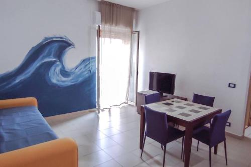 un salon avec une table et une peinture d'une vague dans l'établissement Blue Wave Holiday House, à Aci Castello
