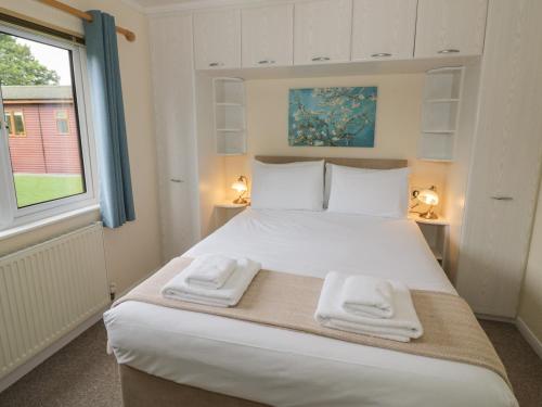 um quarto com uma grande cama branca com toalhas em Snowdrop em Leominster