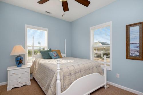 a bedroom with a white bed and two windows at This Is It by Oak Island Accommodations in Oak Island