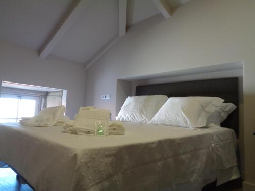 a bed with white pillows and towels on it at Rua Grande Hotel in Viana do Castelo