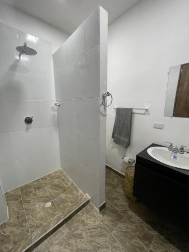 baño blanco con ducha y lavamanos en Casa Del Río en Montería