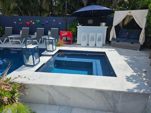 una piscina en un patio con sillas y sombrilla en Casa806 Men Only Guest House en Fort Lauderdale