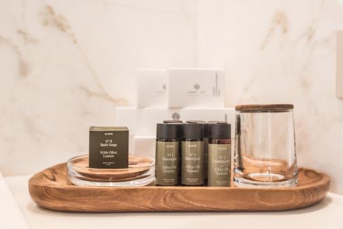 a wooden tray with three bottles and a glass at Νumi Boutique Hotel in Mýkonos City