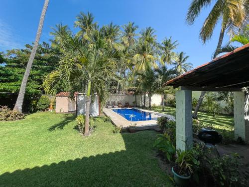 a backyard with a swimming pool and palm trees at Casa De Playa El Encanto in El Porvenir