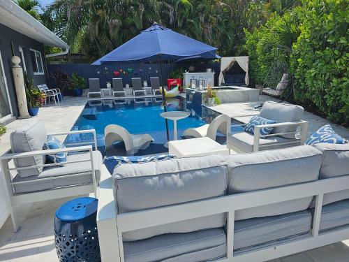 a patio with chairs and a pool with a blue umbrella at Casa806 Men Only Guest House in Fort Lauderdale