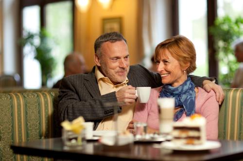 a man and woman sitting at a table drinking coffee at Ensana Nové Lázně in Mariánské Lázně