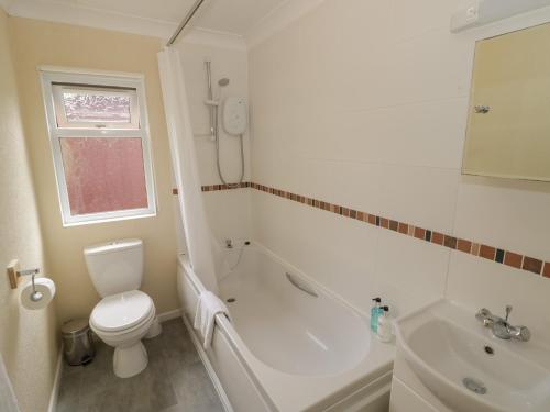 a bathroom with a toilet and a tub and a sink at Rose in Leominster