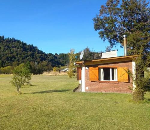 una pequeña casa de ladrillo en un campo de hierba en La Adelfa en Esquel