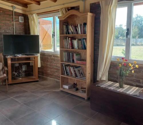 ein Wohnzimmer mit einem TV und einem Bücherregal in der Unterkunft La Adelfa in Esquel