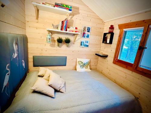a small bedroom with a bed in a wooden wall at Cesemino Farmhouse in Czyżemin
