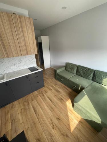 a living room with a green couch and wooden floors at Airport Apartment View Self Check-In Free parking in Vilnius