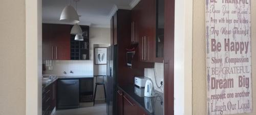 a kitchen with wooden cabinets and a refrigerator at Entire 4 bedroom house in Midrand, Johannesburg in Randjesfontein