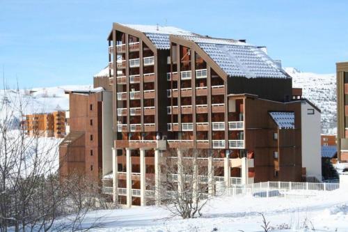 un grand bâtiment dans la neige devant une ville dans l'établissement APPARTEMENT 310 ECRIN D'HUEZ, à L'Alpe-d'Huez