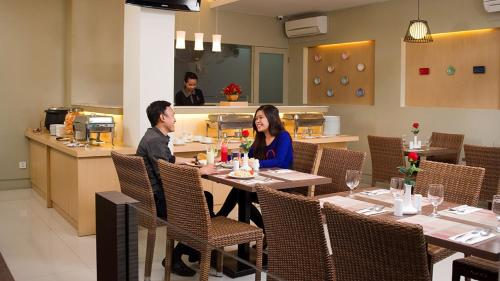 un hombre y una mujer sentados en una mesa en un restaurante en Harlys Residence, en Yakarta
