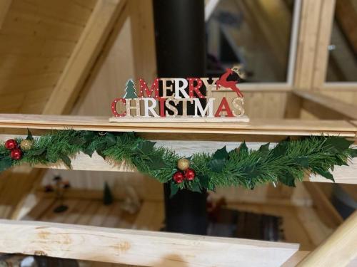 a christmasreath on a wooden table with a merry christmas sign at Cabanutze Satic in Rucăr