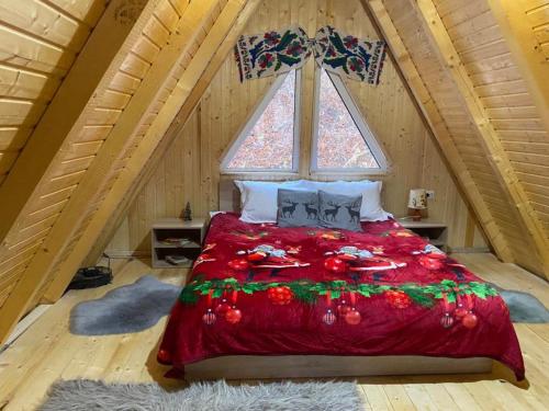 a bedroom with a red bed in a attic at Cabanutze Satic in Rucăr