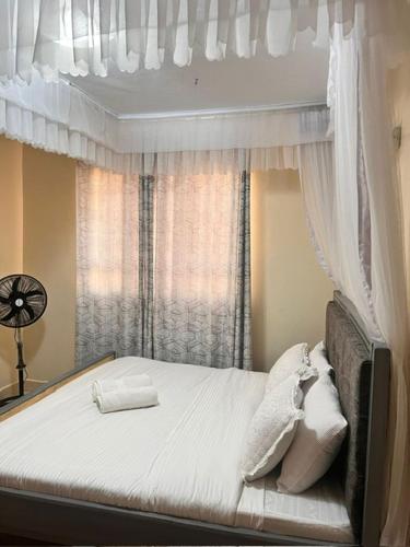 - une chambre avec un lit à baldaquin et une fenêtre dans l'établissement J'Melot Adobas Apartment, à Kisumu