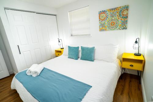 1 dormitorio con 1 cama blanca grande con almohadas azules en Casita-stylish Garden Home 5 Min To Bayshore Water, en Tampa