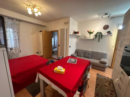 a living room with a red table and a couch at monolocale in centro in Asiago