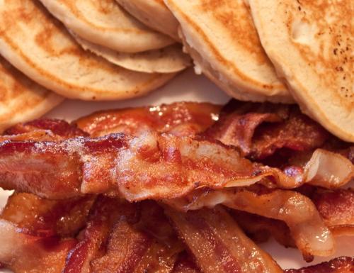 a pile of bacon and pancakes on a plate at Emerald Sea Resort in Ngwesaung