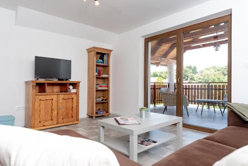 a living room with a tv and a couch at Berkenyeliget Vendégház in Szigliget