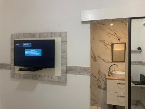 a bathroom with a television on a wall at Comme chez soi 2 in Tchimbanmba