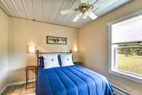 a bedroom with a blue bed with a ceiling fan at Serene Belgrade Hideaway with Fire Pit and Grill! 