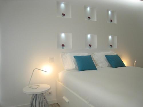 a white bedroom with a white bed with blue pillows at Cascais FEELINGS in Cascais