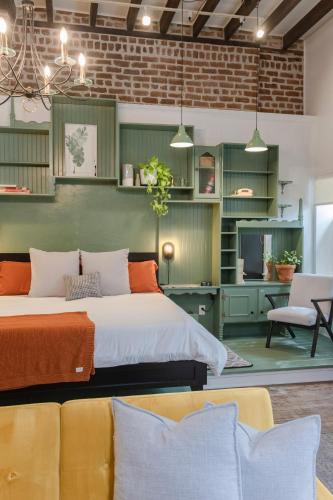 two beds in a room with green cabinets and a couch at 1885 Garden Studio - Historic Heart of Savannah - Pulaski Ward in Savannah
