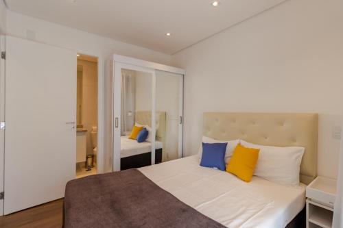 - une chambre avec un lit doté d'oreillers jaunes et bleus dans l'établissement 360 Summit Pinheiros, à São Paulo