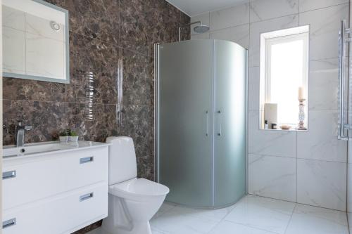 a white bathroom with a toilet and a shower at The Rose Valley room in a shared villa in Gothenburg