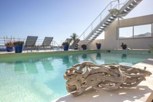a swimming pool with a piece of drift wood in front of it at LES SUITES LOVE 3 SPA VUE MER PISCINe in Marseille