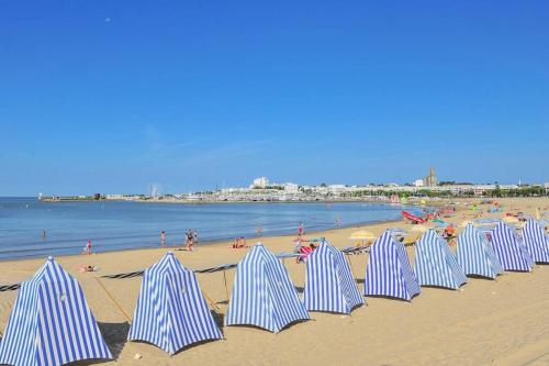un groupe de parasols rayés bleus et blancs sur une plage dans l'établissement Joli studio à 3 min de la plage - rénové en avril 2025, à Royan