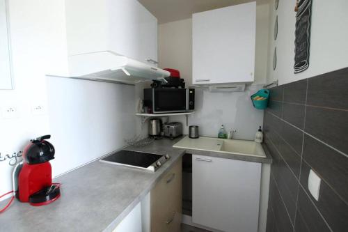 a small kitchen with white cabinets and a sink at Joli studio à 3 min de la plage in Royan
