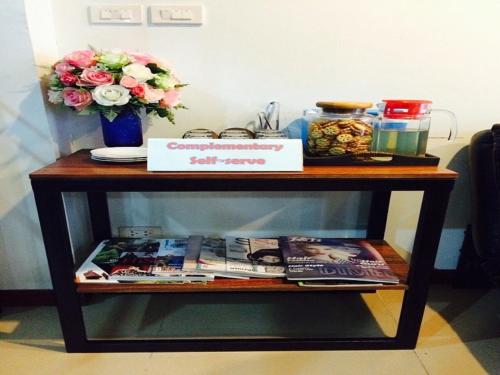 a wooden table with a shelf with magazines and flowers at Double DD House at MRT Sutthisarn in Bangkok