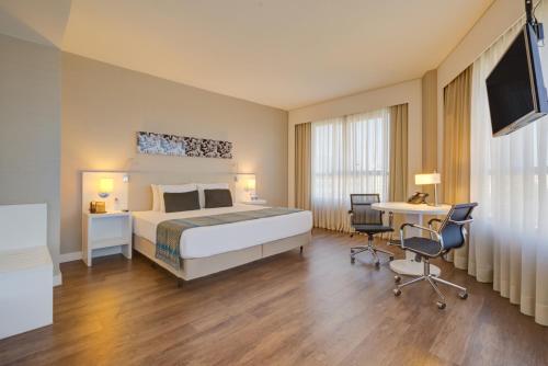 サン・カエタノ・ド・スルにあるQuality Hotel São Caetanoのベッド、テーブル、椅子が備わるホテルルームです。