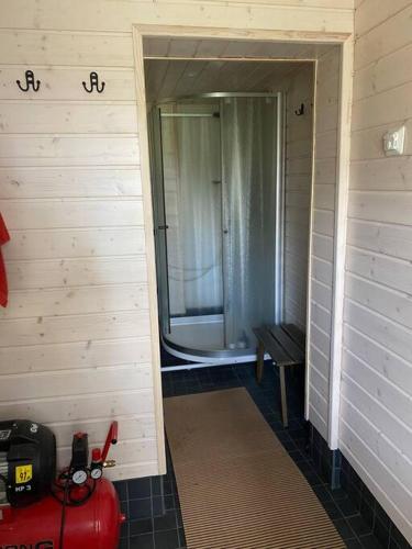 a bathroom with a shower and a door with a bench at Villa Salajärvi in Heinola