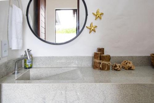 een badkamer met een wastafel en een spiegel bij Casa Milagres 03 suítes - 300m da Praia, 6 pessoas in Pôrto de Pedras