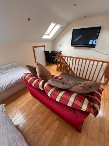 a bedroom with a red couch and a flat screen tv at Luxury Home in Dublin WiFi TV B&B Close to City Centre in Lucan