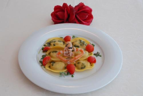 a white plate of food with vegetables on a table at Hotel Amburgo in Bibione