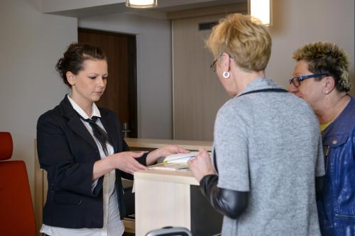 three people standing around a desk in an office at Hotel Trojan in Lądek-Zdrój