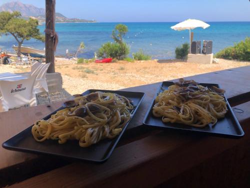 dos platos negros de espagueti en una mesa cerca de la playa en Tenda, en Tertenìa